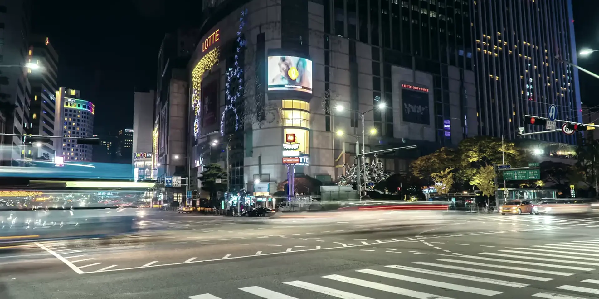 Cruce urbano de noche, con el rastro de luz del tráfico